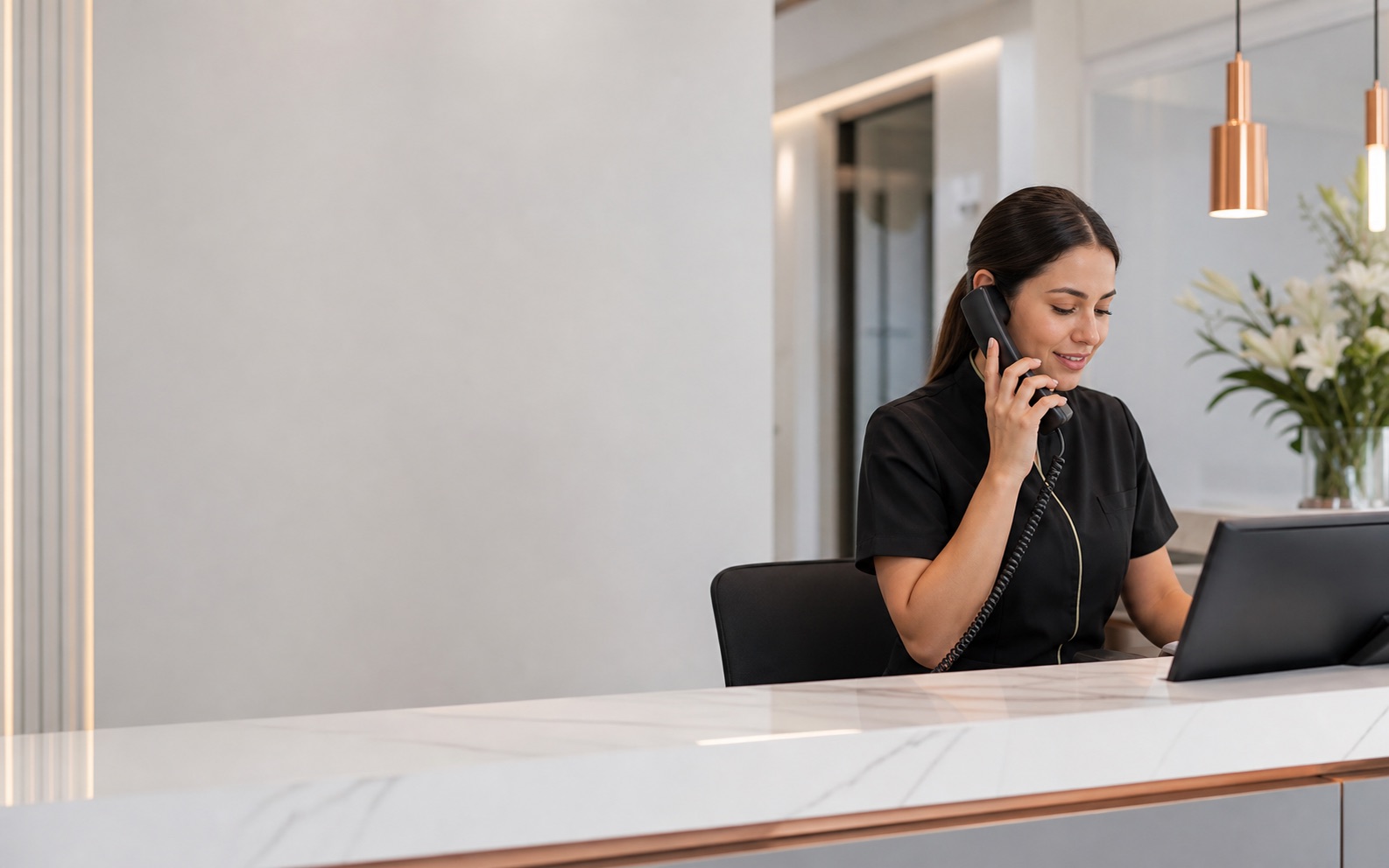 Recepcionista de clinica atendiendo una llamada mientras gestiona citas